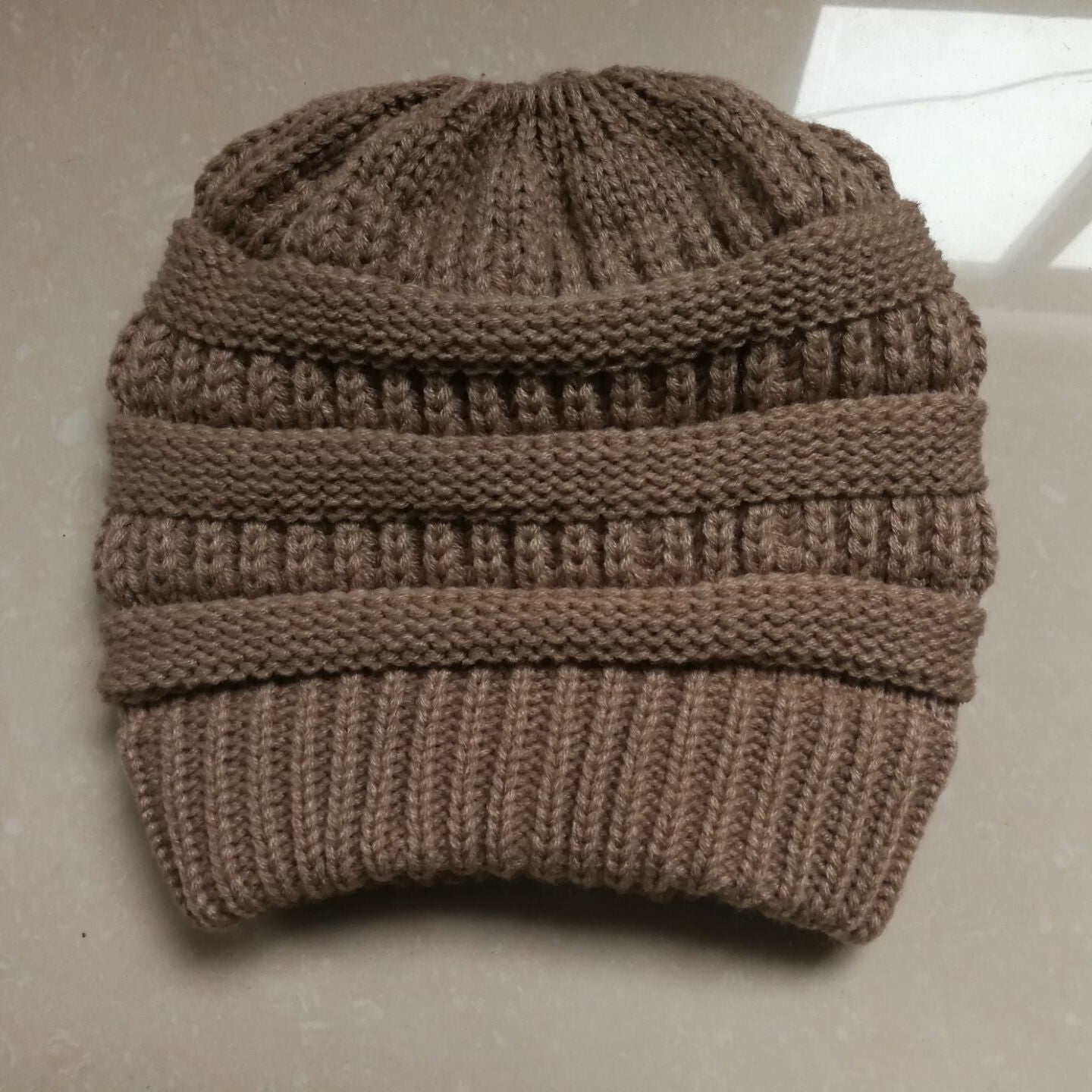Brown knitted beanie on a light-colored surface