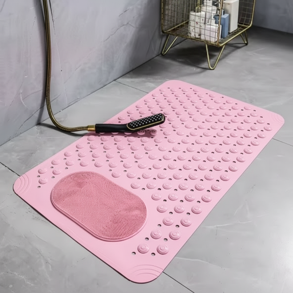Light pink bath mat on a gray floor with a pink towel and brush.
