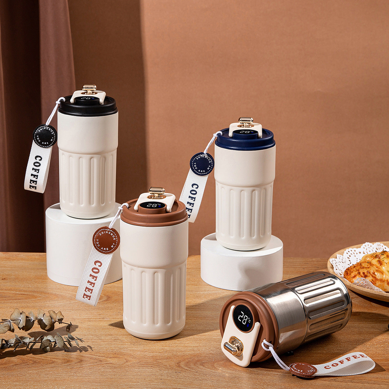 Set of white coffee tumblers with different colored lids on a wooden surface.