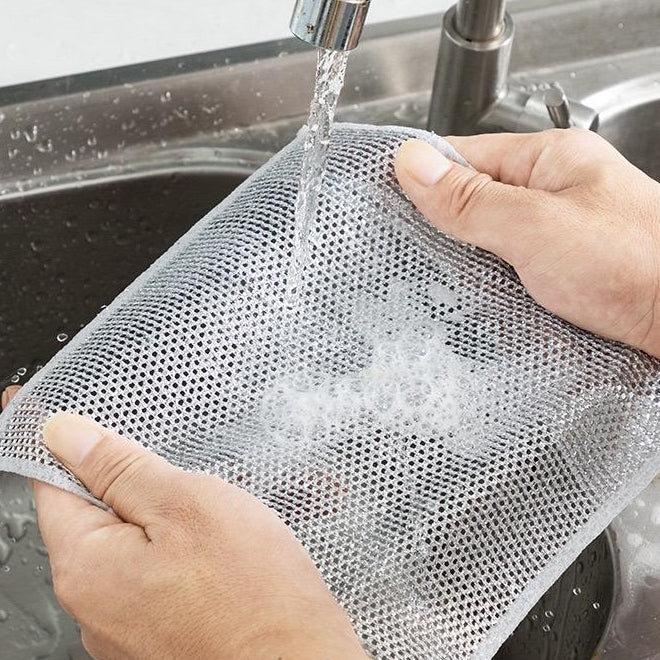 Person washing a mesh bag under running water in a sink with text on the screen.