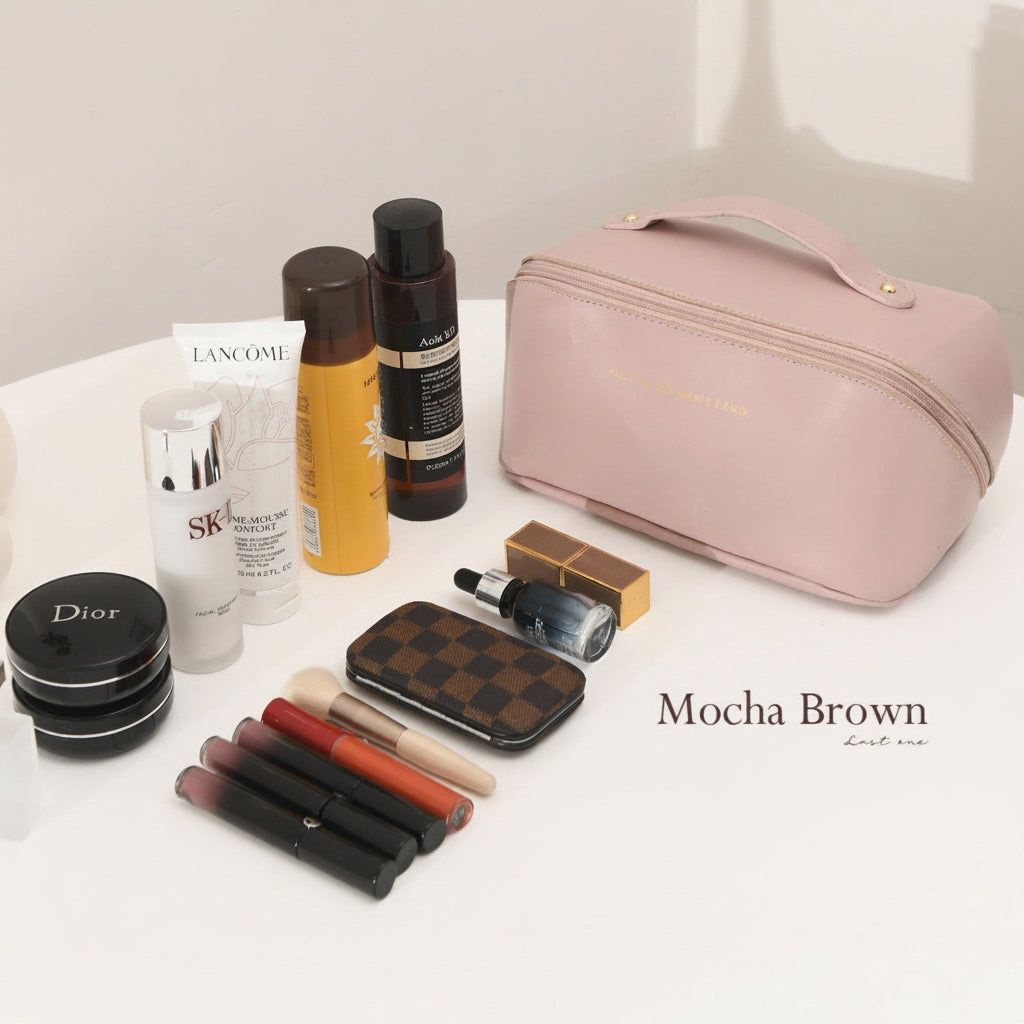 Pink cosmetic bag with makeup items on a white surface