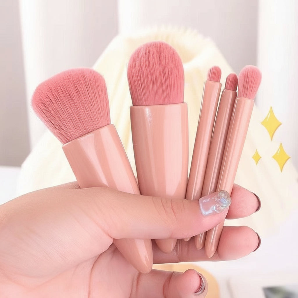 Set of pink makeup brushes held by a hand with a blurred background